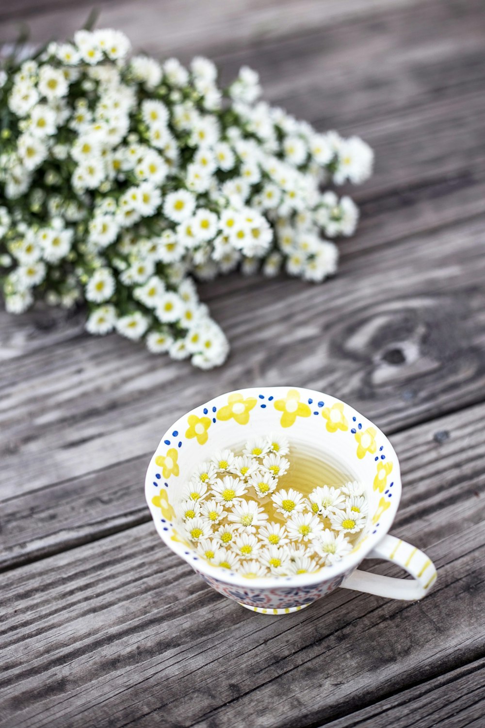 テーブルの上に花が飾られた白と黄色のカップ