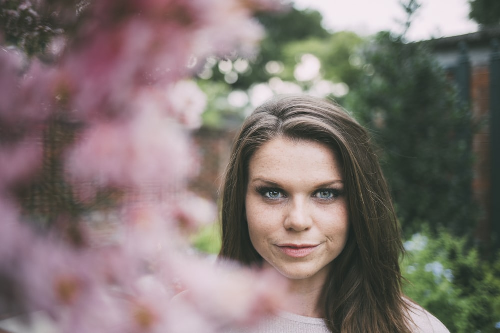shallow focus photography of woman surrounded by flowers during daytime