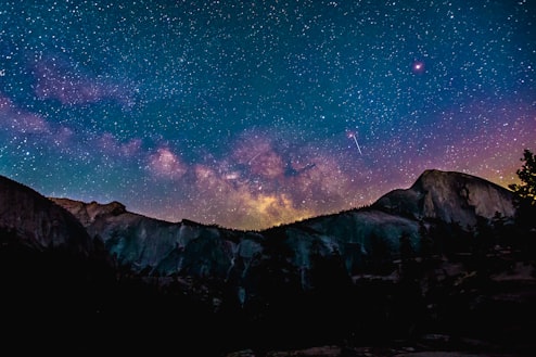Dimly lit mountains give way to a starry night showing the Milky Way