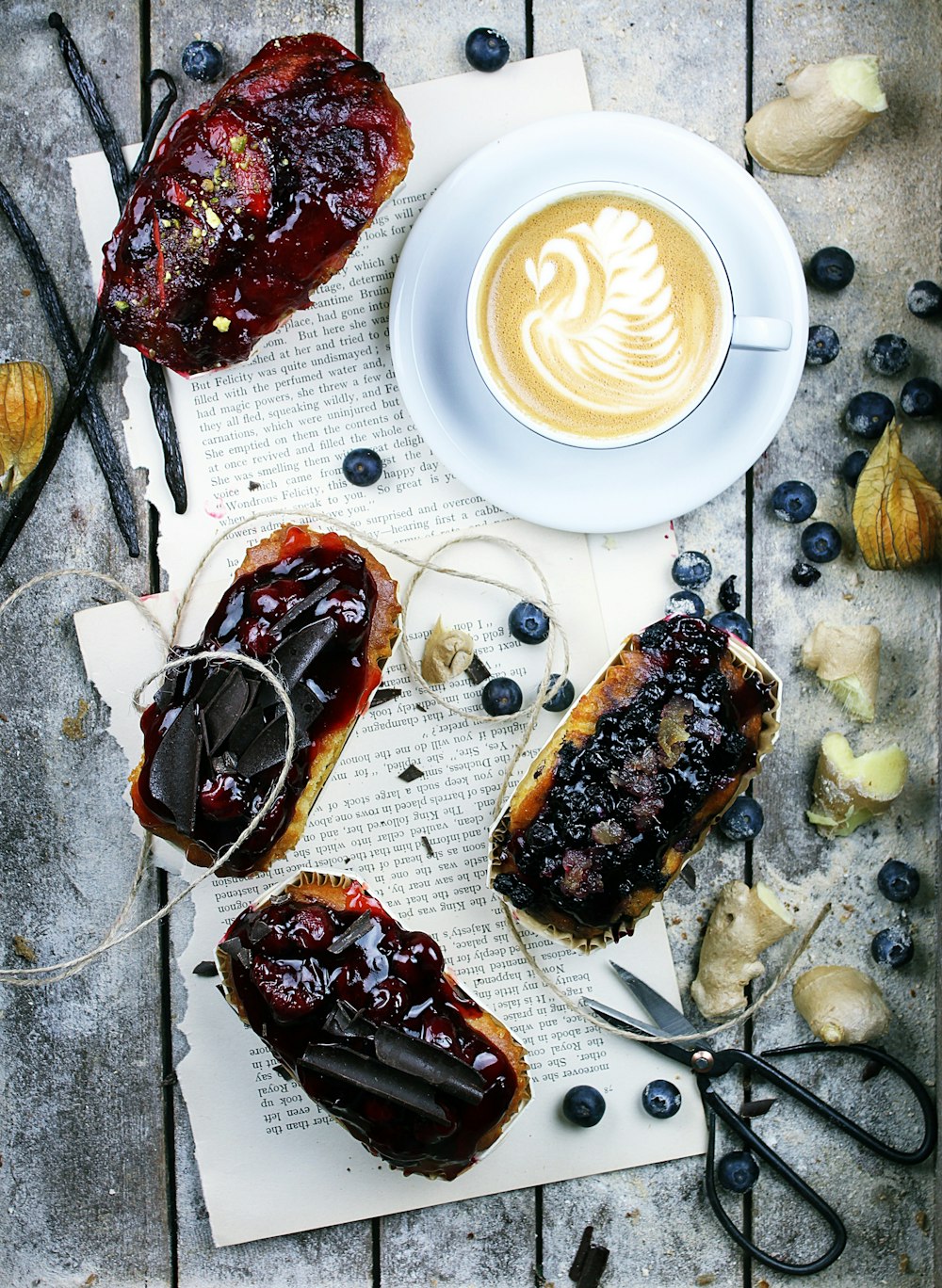 torte di frutta, cappuccino e mirtilli su pannello di legno grigio