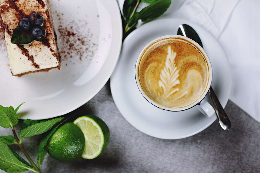 flat lay photography of coffee in teacup near plate of sliced cake