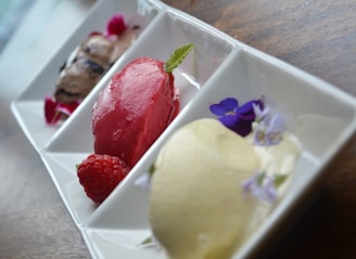A vibrant rainbow sorbet trio served in a clear glass bowl with a silver spoon