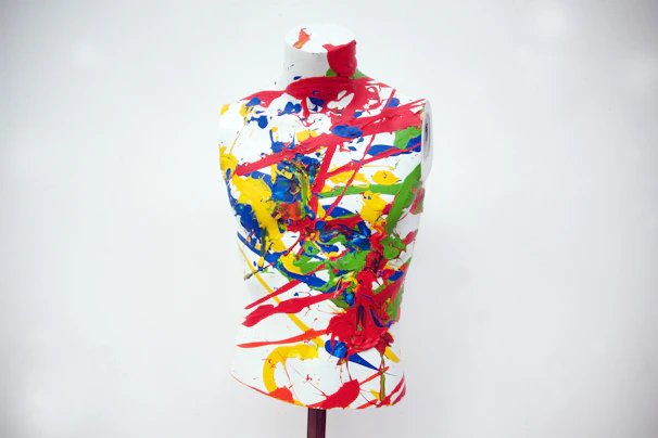 A model wearing a bright graphic tee with an artistic splash of paint and bold brush strokes.