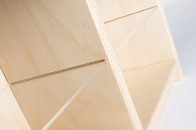 A stylish storage box with a soft matte finish holding craft supplies on a wooden shelf.