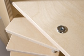 A close-up view of a wooden construction, likely a piece of furniture with multiple stacked shelves. A metal washer or fastener is embedded into the wood on the top shelf.