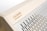 The image features a wooden structure with a carved name and website link engraved on the surface. Adjacent to the wooden area is a metallic section with evenly spaced vertical slits, providing a sleek and modern design.