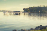 A serene lakeside view with reflections of surrounding trees and a wooden dock.