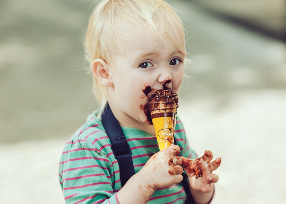 boy in red and white striped polo shirt holding ice cream cone