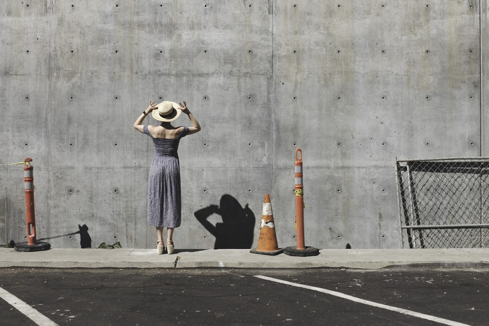 femme en robe grise face à un mur