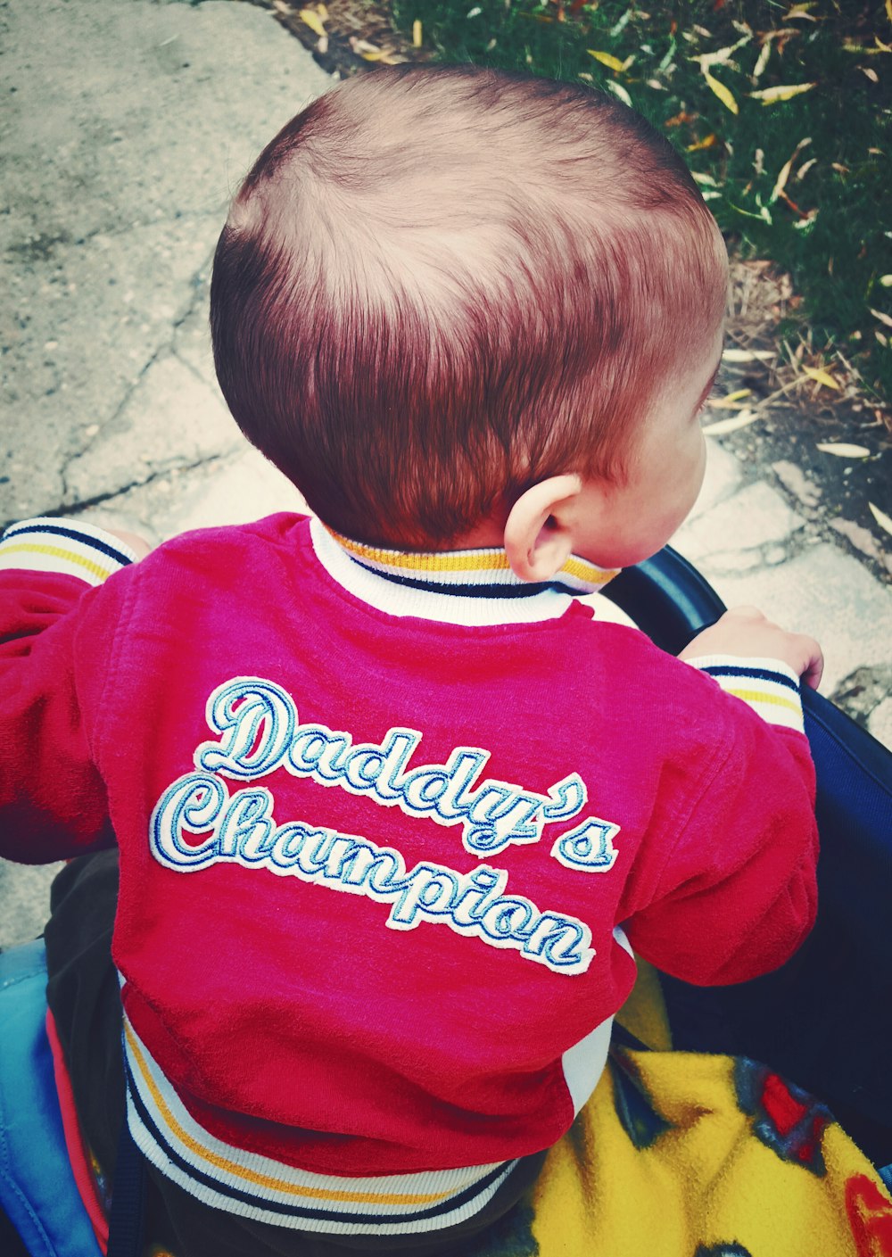 A boy wearing a sweatshirt that says "Daddy's Champion," on the back.