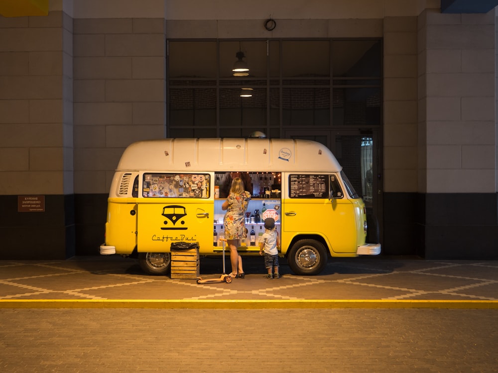 Mujer y niño de pie frente a un autobús amarillo en el estacionamiento