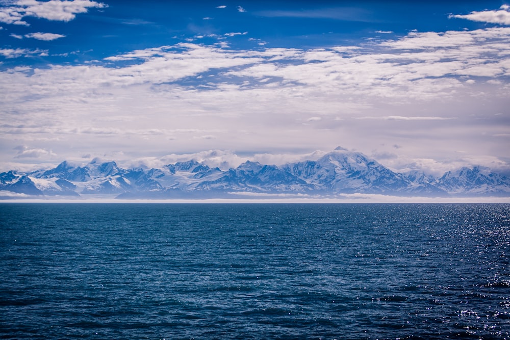 photographie de paysage de la chaîne de montagnes enneigée à travers le plan d’eau