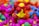 Colorful interlocking plastic toys are scattered in a pile, predominantly featuring bright colors such as pink, red, yellow, blue, and green. The foreground showcases a structure with ball-and-stick elements, giving a playful and vibrant impression.
