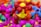 Colorful interlocking plastic toys are scattered in a pile, predominantly featuring bright colors such as pink, red, yellow, blue, and green. The foreground showcases a structure with ball-and-stick elements, giving a playful and vibrant impression.