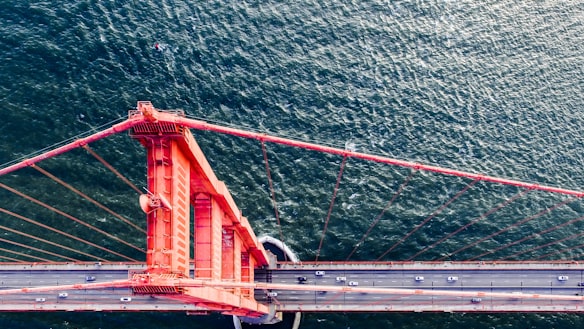 Looking down over one of the pillars of the Golden Gate Bridge to the roadside and water below