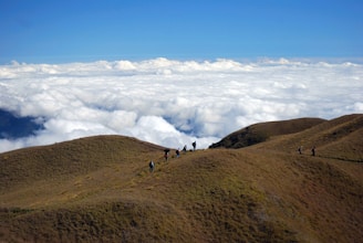 A group of travelers trekking along a mountain ridge under a clear blue sky.