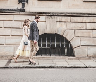 man and woman walking beside a road during daytime