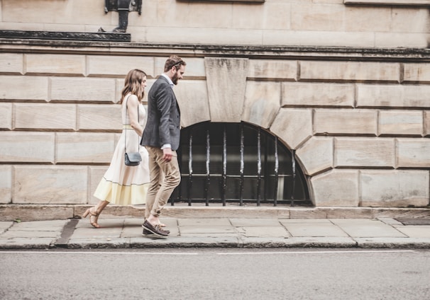 man and woman walking beside a road during daytime