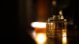 Artistic shot of a perfume spray misting gently over a warm amber backdrop.