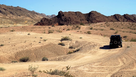 black SUV on road near rock mountain under blue sky during daytime in Las Vegas United States