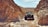 A rugged off-road truck navigating through a rocky terrain under a clear blue sky.