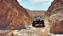 A rugged Jeep climbing a rocky trail under a clear blue sky, showcasing off-road adventure.