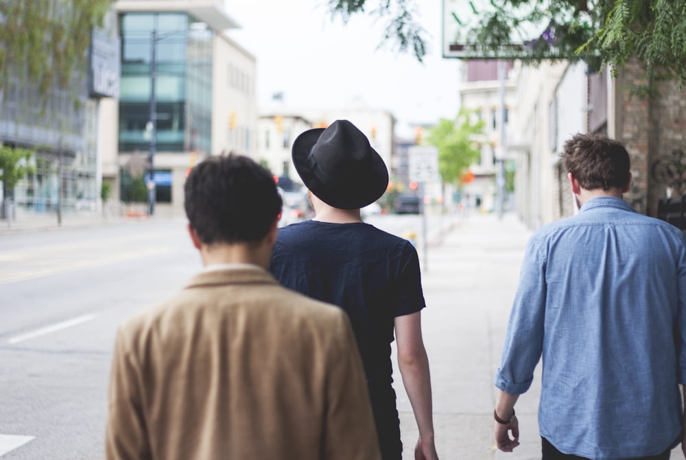 trois hommes marchant le long de la rue