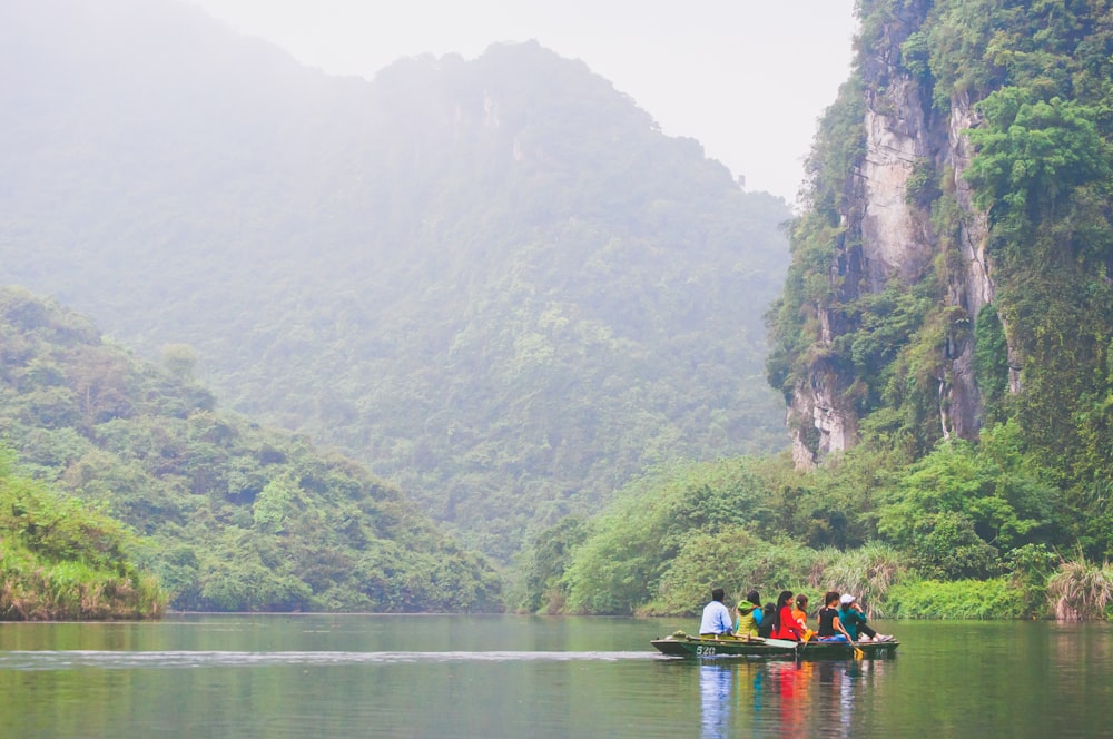 personnes dans un bateau dans l’eau près des montagnes pendant la journée