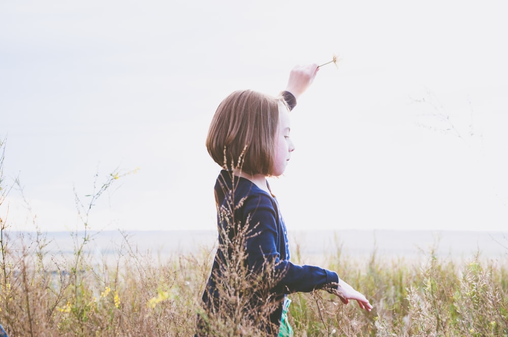 fille sur le champ d’herbe sous le ciel blanc