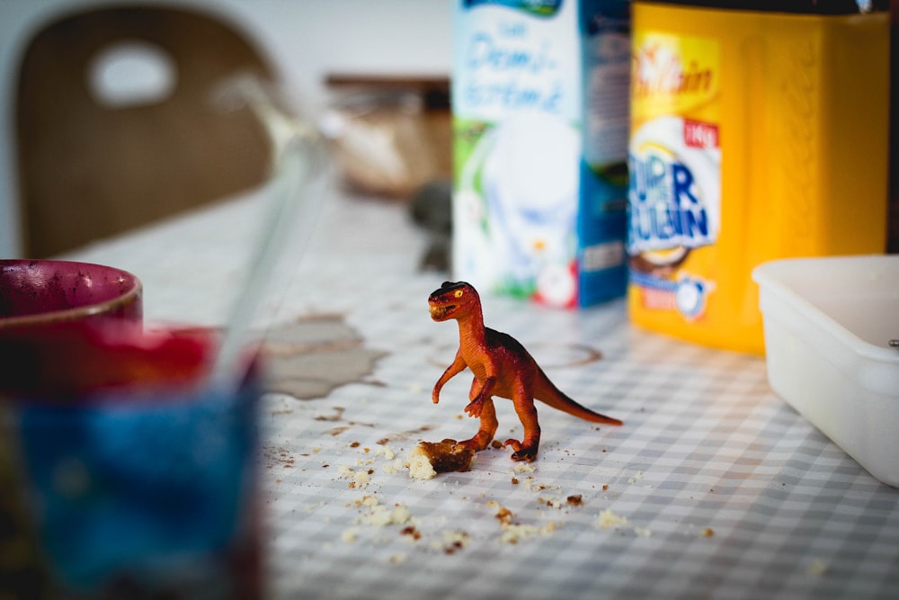 Um pequeno dinossauro de brinquedo na mesa da cozinha.