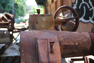 Close-up of a worker applying industrial anticorrosive coating on heavy machinery in a rugged outdoor setting.