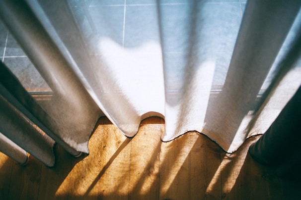 Sunlight streaming through sheer curtains into a tranquil room set up for meditation or gentle yoga.