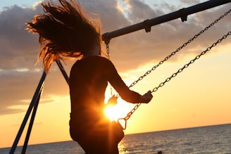 woman riding on swing during sunset