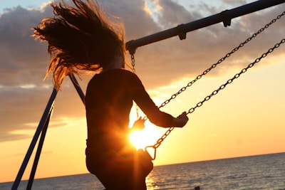 woman riding on swing during sunset