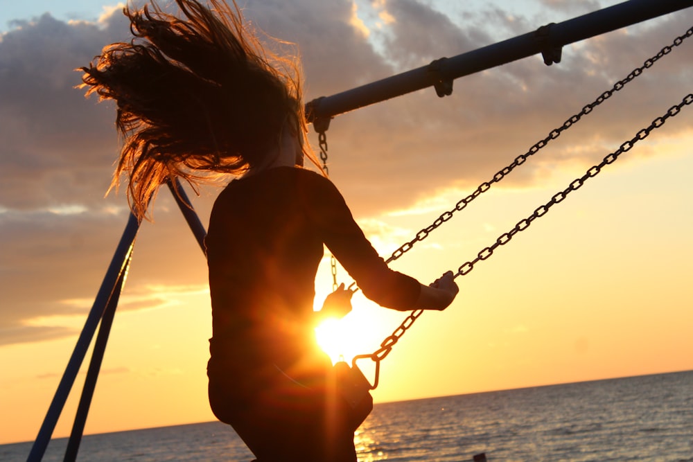 femme équitation sur balançoire au coucher du soleil