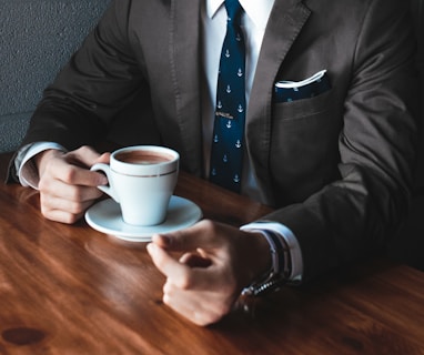 man holding cup filled with coffee on table