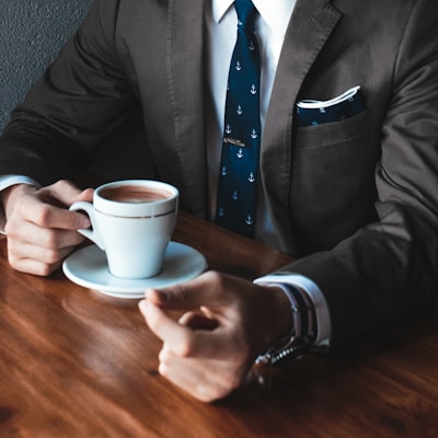 man holding cup filled with coffee on table