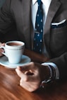 man holding cup filled with coffee on table