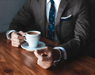 man holding cup filled with coffee on table