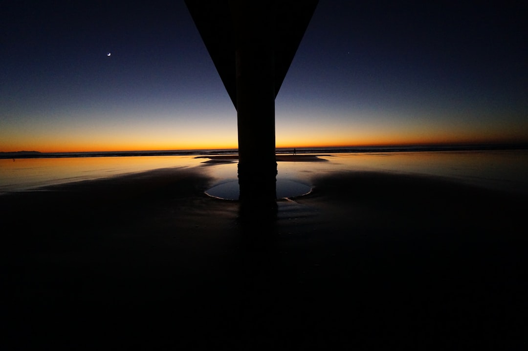 The sun-kissed horizon looms behind the pillar and across the water at dusk at New Brighton