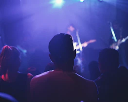An artist performing live under moody, dim lighting with a focused crowd.