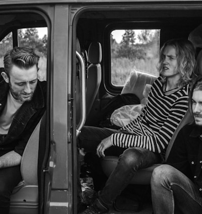 grayscale photo of three men sitting on vehicle seats