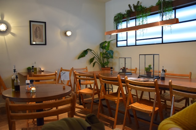 Cozy coffee shop interior with natural wooden furniture and green plants creating a warm atmosphere.