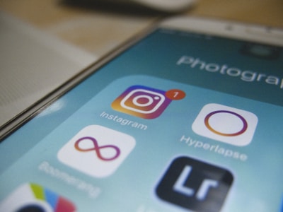 A close-up of a smartphone screen displaying a folder labeled 'Photography' with several app icons. The Instagram app icon is prominently shown with a notification badge, indicating a new message or activity. Other visible apps include Hyperlapse, Boomerang, and Lightroom.