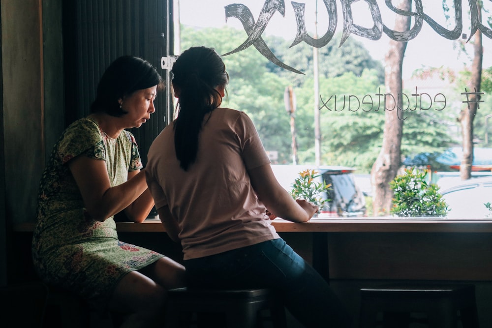 women sitting on black wooden stools