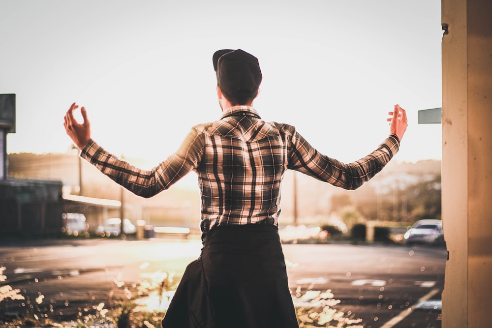 a man standing in a parking lot with his arms outstretched