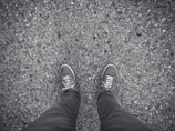 An outdoor scene showing shoes stepping on a textured urban pavement.