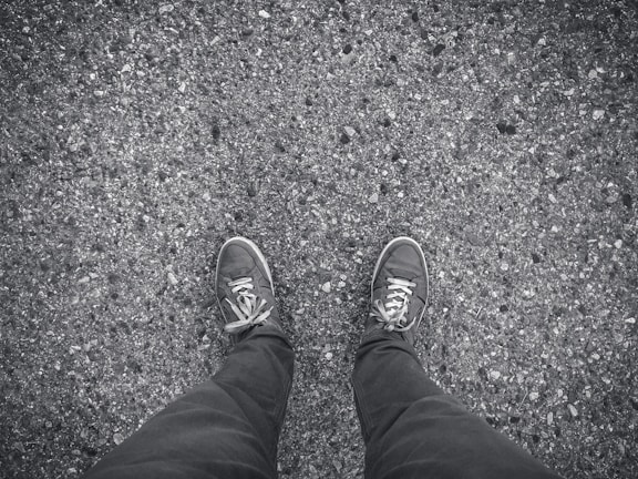 An outdoor scene showing shoes stepping on a textured urban pavement.