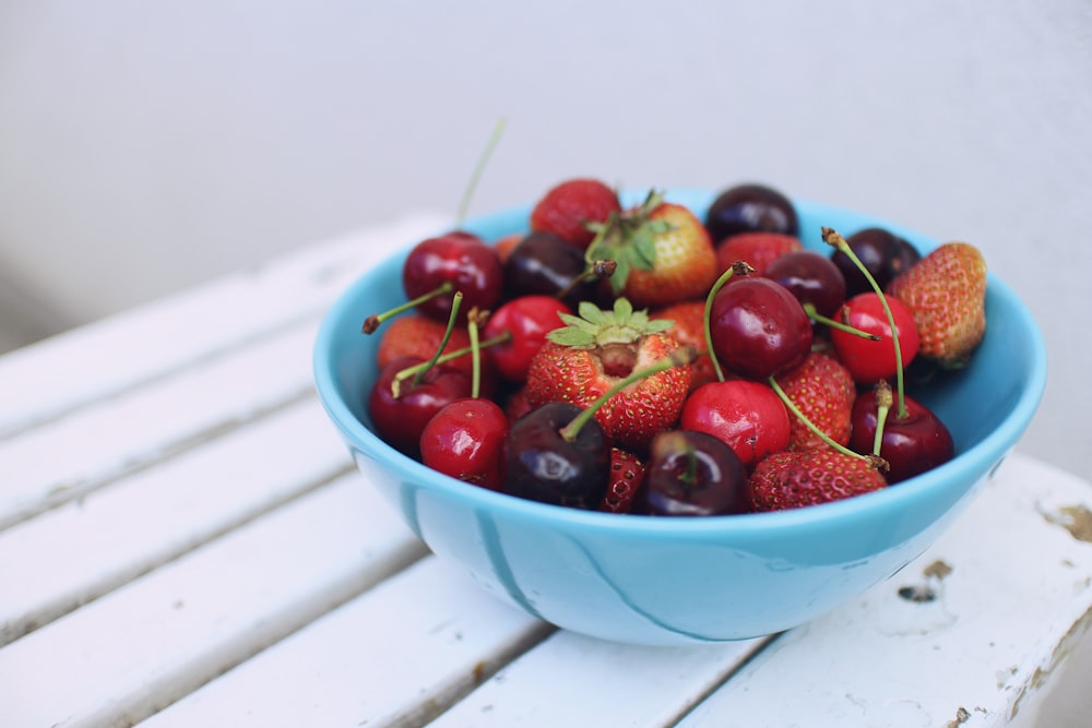 Enfoque fotográfico de fresas y cerezas en cuenco azul