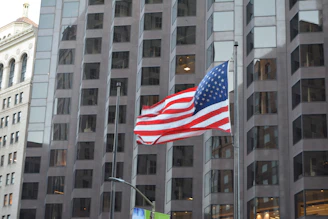 A modern office building with American flag colors subtly reflected in the glass windows.